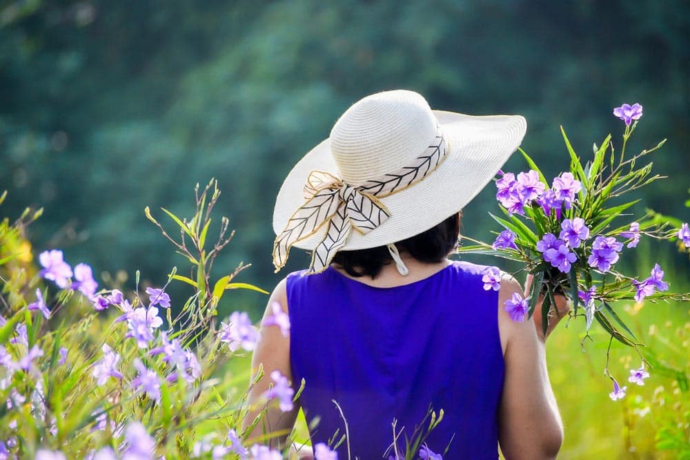 A woman with a wide-brimmed hat to protect her eyes from the summer sun.