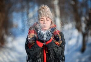 Woman blowing snow outdoors to illustrate how to take care of your eyes this winter